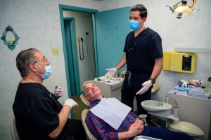 both Peckville dentists in room speaking with male patient